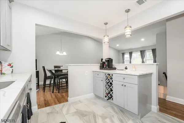 a kitchen with kitchen island a sink a stove a dining table and chairs with wooden floor
