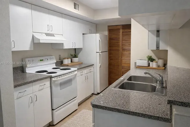 a kitchen with granite countertop a sink a stove and refrigerator