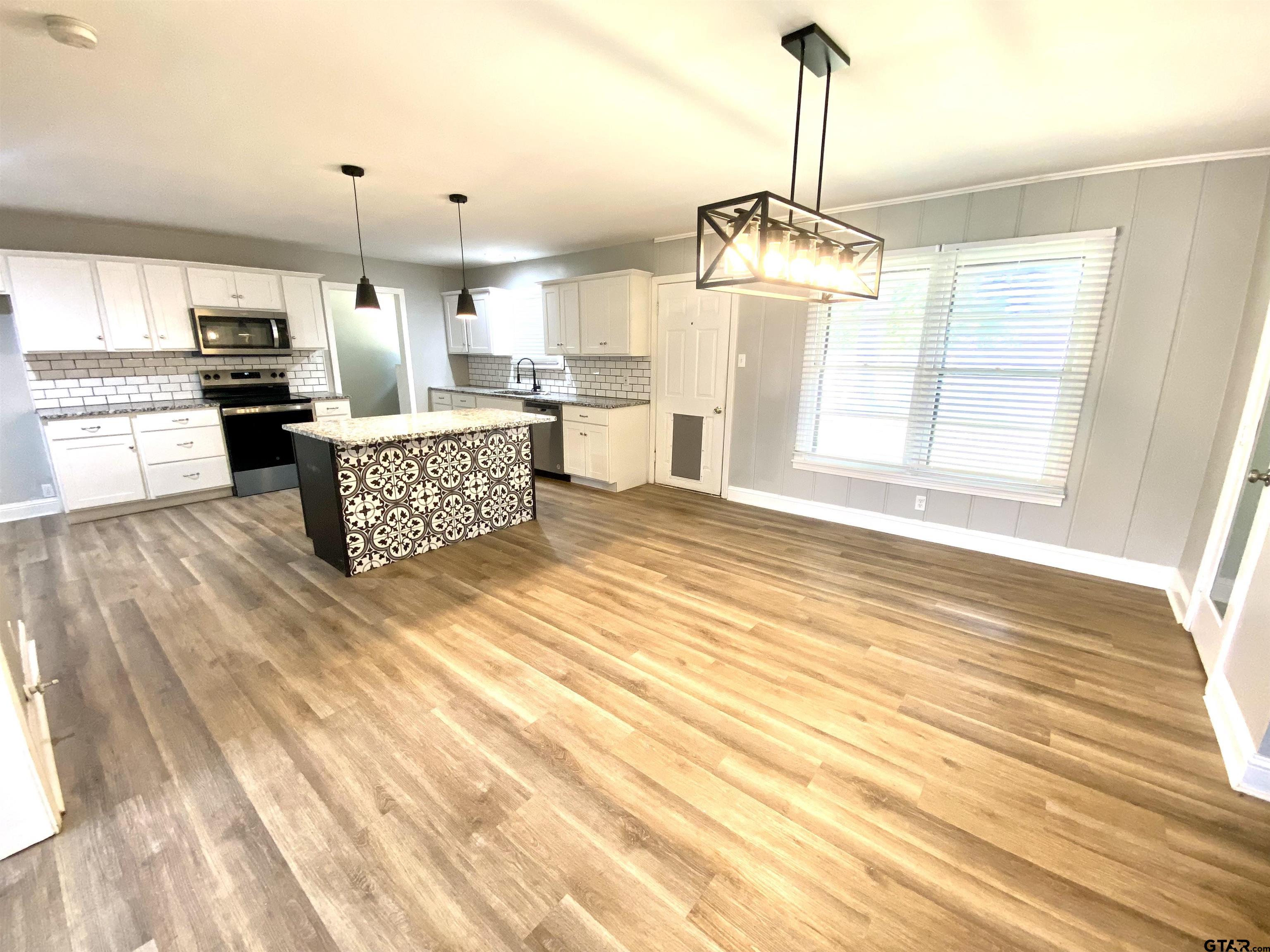 1914 Parklen Street Tyler, TX 75701 - Photo 4 of 39 a open kitchen with granite countertop a stove a sink dishwasher and a fireplace with wooden floor