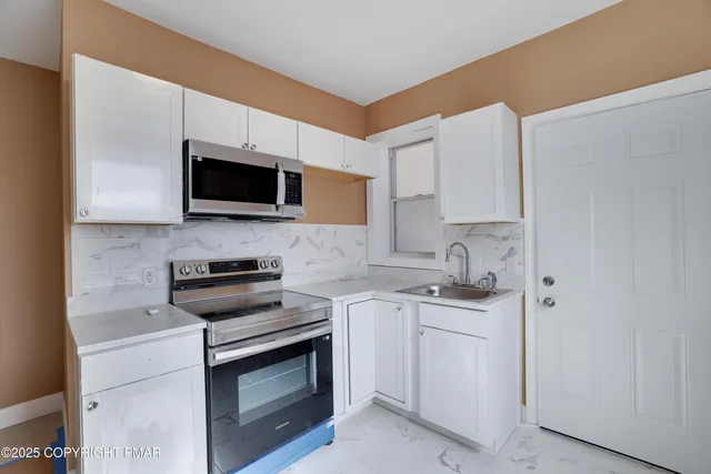 a kitchen with stainless steel appliances a stove microwave and sink