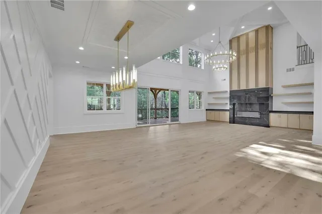 an empty room with wooden floor and chandelier fan