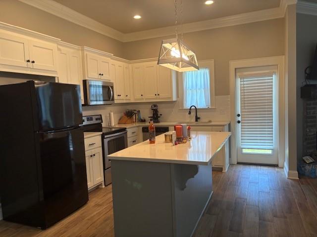 6896 Bethany Reed Circle Blanchard, LA 71107 - Photo 3 of 9 Modern kitchen featuring white cabinetry, a light-toned island with an integrated countertop, stainless steel appliances, wood-finish flooring, and crown molding