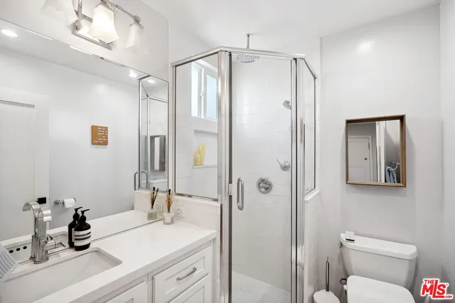 a bathroom with a shower sink vanity mirror and toilet
