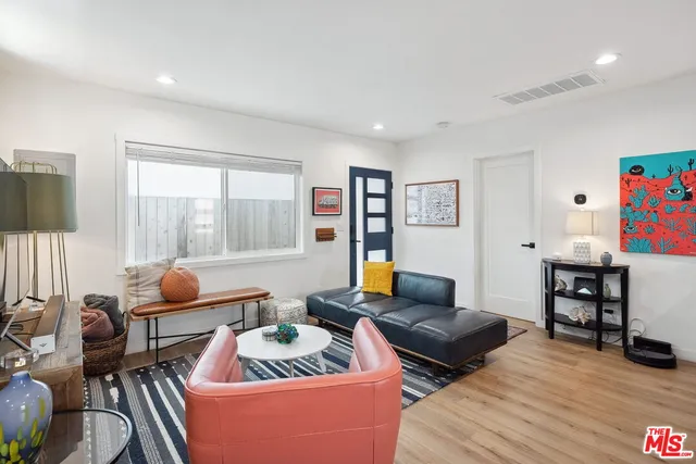 a living room with furniture kitchen view and a wooden floor