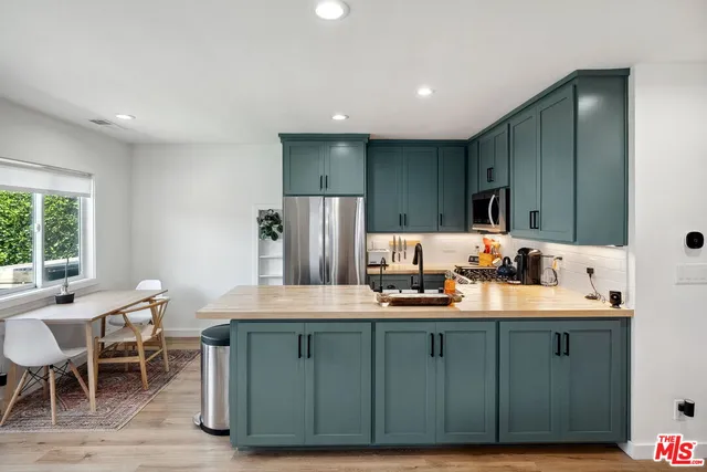 a kitchen with kitchen island granite countertop a sink a stove a refrigerator cabinets and dining table