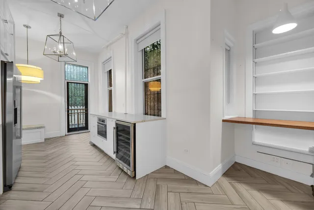 a view of a hallway with wooden floor and a chandelier