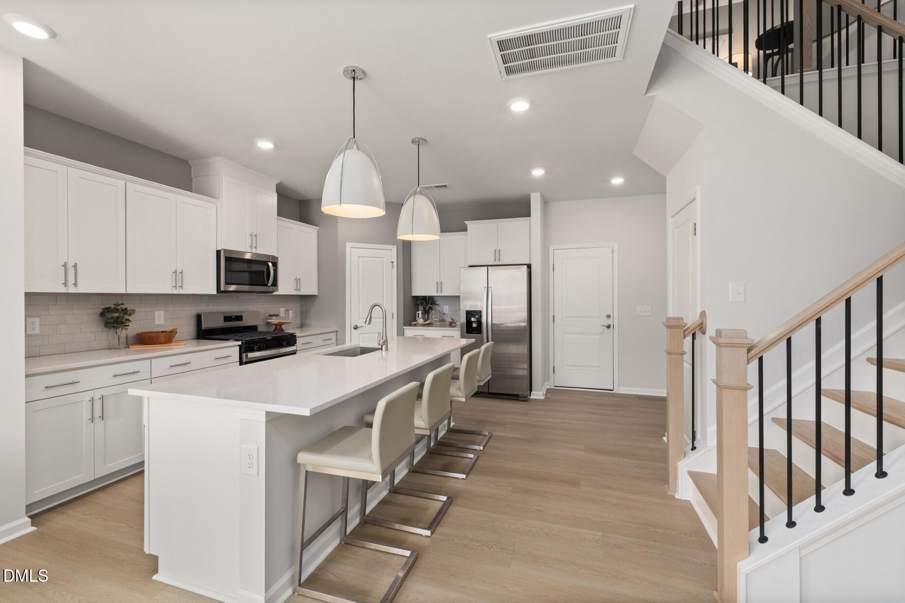 2913 Denson Road Fuquay-Varina, NC 27526 - Photo 6 of 30 a kitchen that has a lot of white cabinets and stainless steel appliances