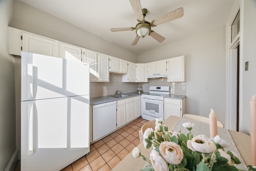 367 Somerville Avenue, Unit G Somerville, MA 02143 - Photo 20 of 39 a kitchen with stainless steel appliances kitchen island granite countertop a sink a stove a refrigerator a microwave a dining table and chairs with wooden floor