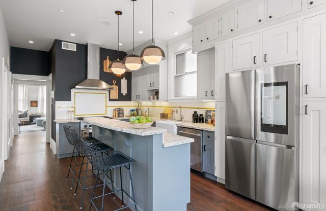 a kitchen with granite countertop a refrigerator a stove a sink dishwasher a dining table and chairs with wooden floor