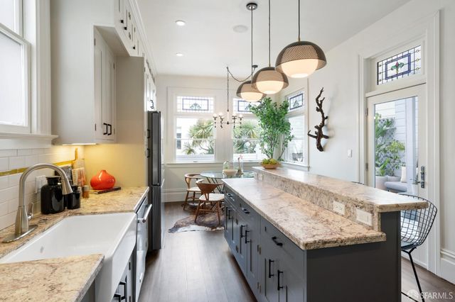 a kitchen with granite countertop a stove a sink and a refrigerator