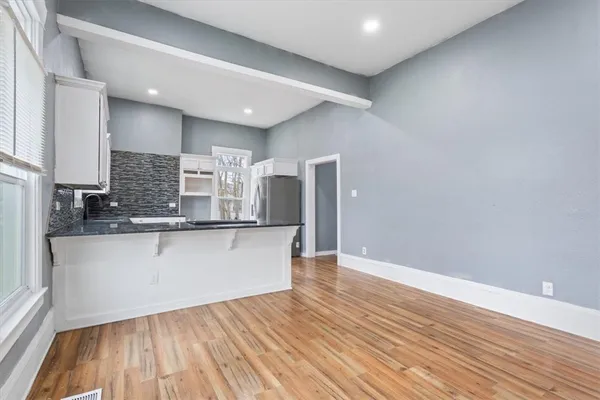 a large kitchen with stainless steel appliances granite countertop a refrigerator a sink and wooden floors