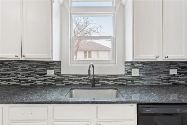 a kitchen with granite countertop white cabinets and a sink