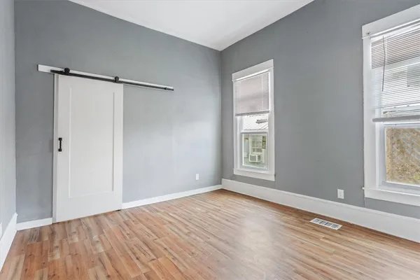 a view of an empty room with wooden floor and a window