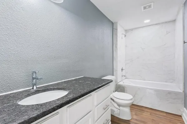 a bathroom with a granite countertop sink toilet and shower