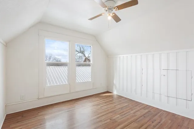 an empty room with wooden floor fan and windows