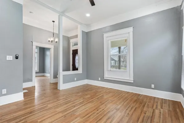 a view of an empty room with wooden floor and a window
