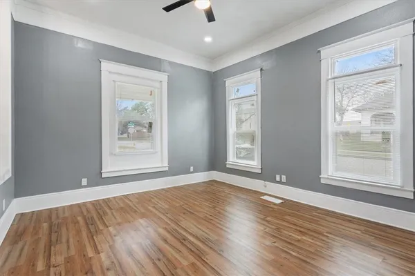 a view of an empty room with window and wooden floor