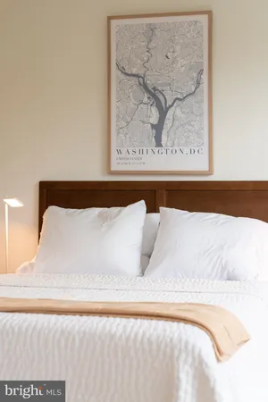 a white bed sitting in a bedroom and painting on the wall