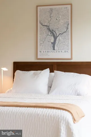 a white bed sitting in a bedroom and painting on the wall