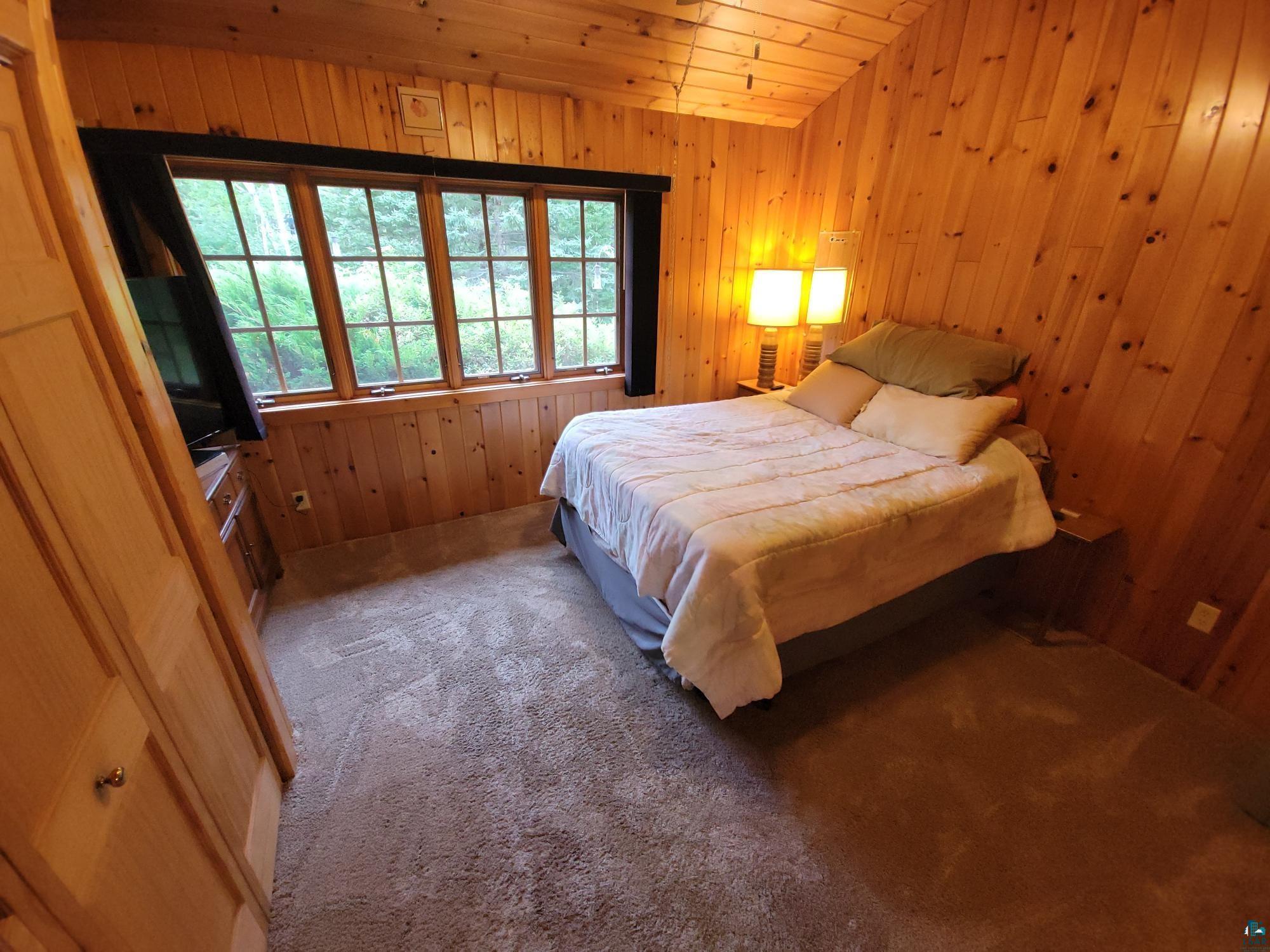 181 Linnell Road Grand Marais, MN 55604 - Photo 57 of 77 Sloped wood-paneled ceiling, wood-paneled walls, carpeted flooring, built-in window, and a built-in wood cabinet