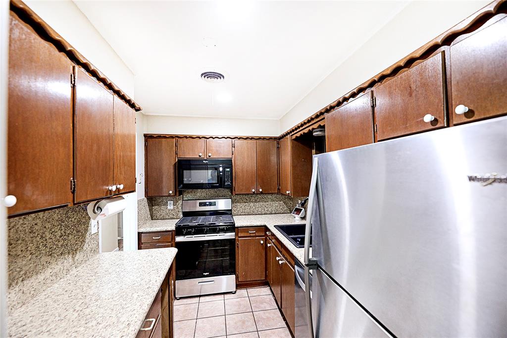 702 Decatur Street Bowie, TX 76230 - Photo 12 of 36 a kitchen with granite countertop a refrigerator and a stove top oven