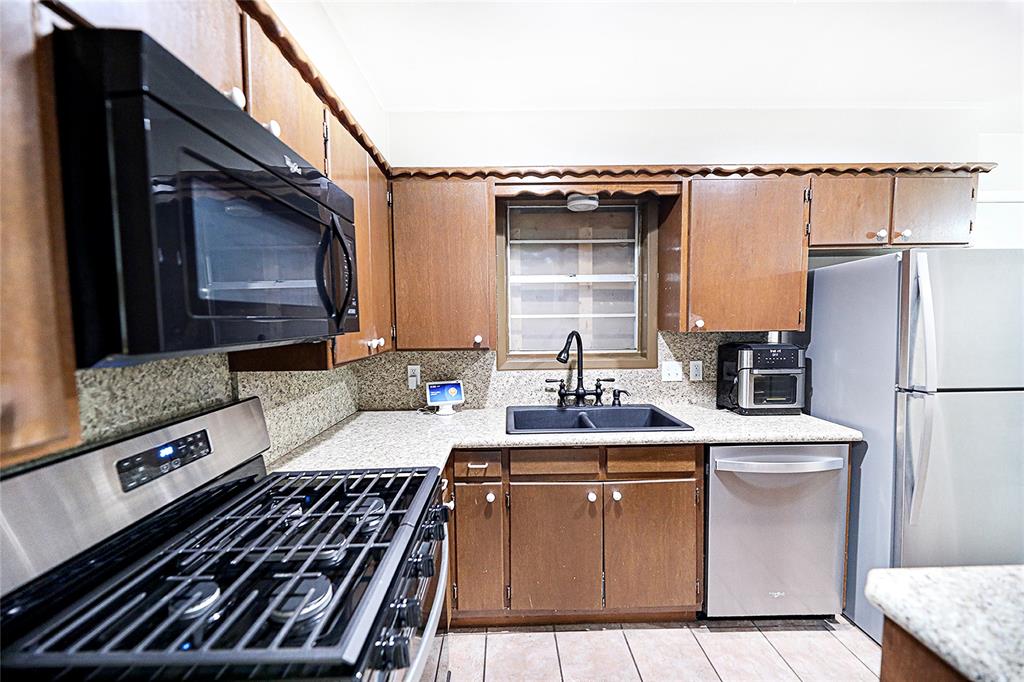 702 Decatur Street Bowie, TX 76230 - Photo 13 of 36 a kitchen with kitchen island granite countertop a sink stove and refrigerator
