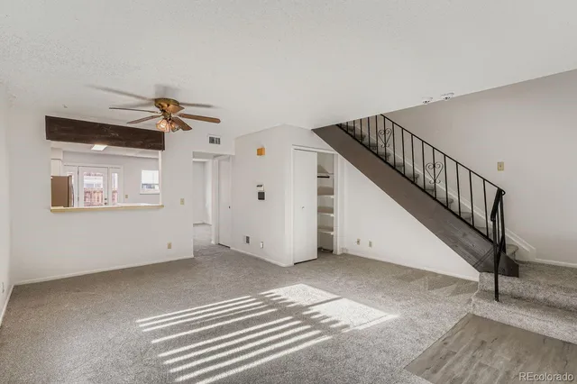 a view of an empty room with stairs and a ceiling fan