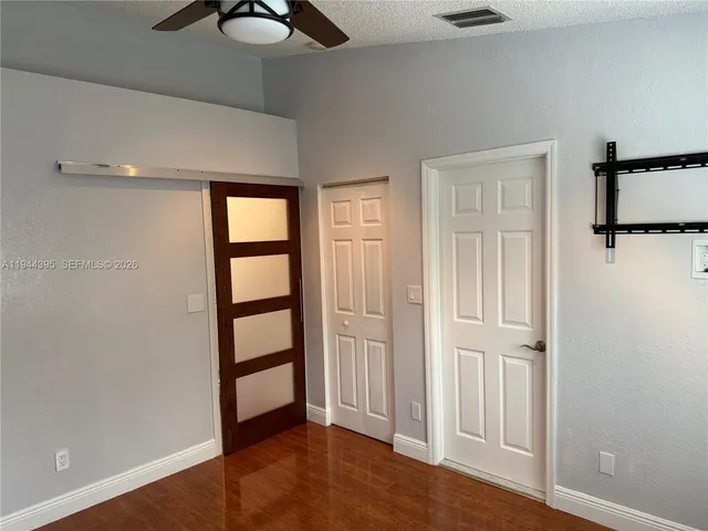 an empty room with wooden floor closet and windows