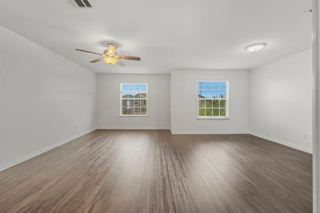 a view of an empty room with a window and wooden floor