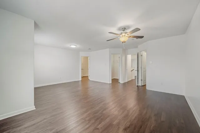 a view of an empty room with a ceiling fan and wooden floor