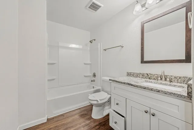 a bathroom with a granite countertop toilet a sink and a bathtub