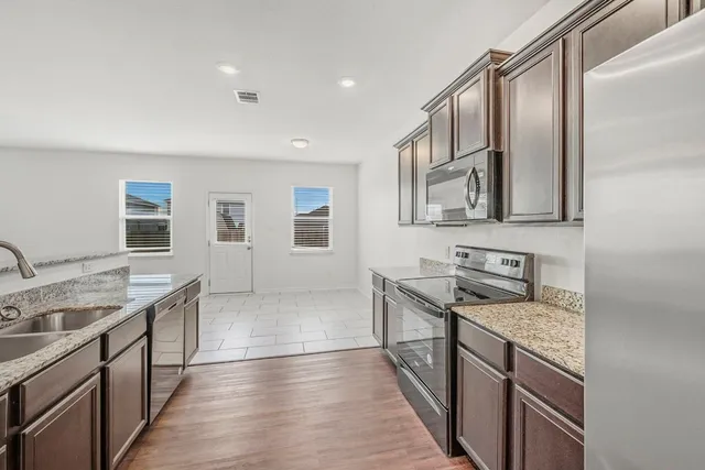 a kitchen with granite countertop a sink stove and cabinets