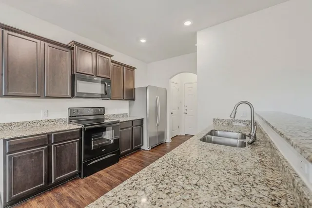 a kitchen with stainless steel appliances granite countertop a stove a sink and a microwave