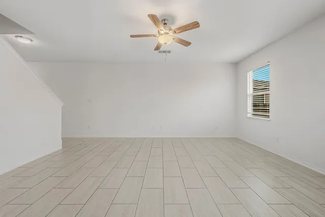 an empty room with white walls and ceiling fan