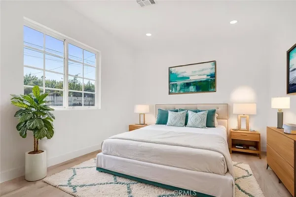 a bedroom with a large bed and a potted plant