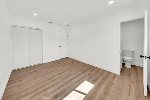 a view of empty room with wooden floor and toilet