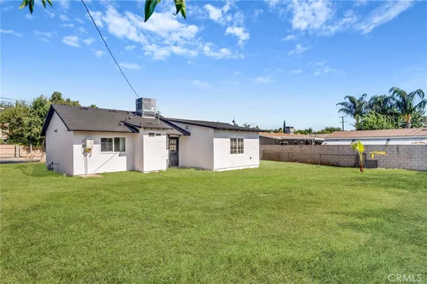 a house that is sitting in the grass with large trees