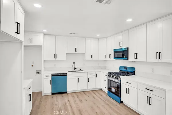 a kitchen with cabinets stainless steel appliances a sink and wooden floor