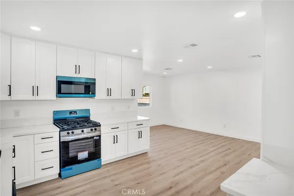a kitchen with granite countertop a stove top oven and cabinets