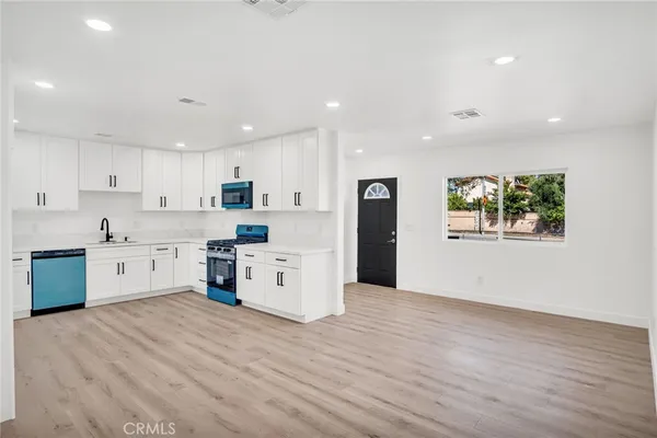 a large kitchen with stainless steel appliances granite countertop a stove a sink and a refrigerator