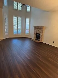 an empty room with wooden floor fireplace and windows