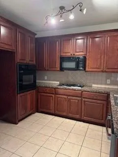 a kitchen with granite countertop a refrigerator and wooden cabinets