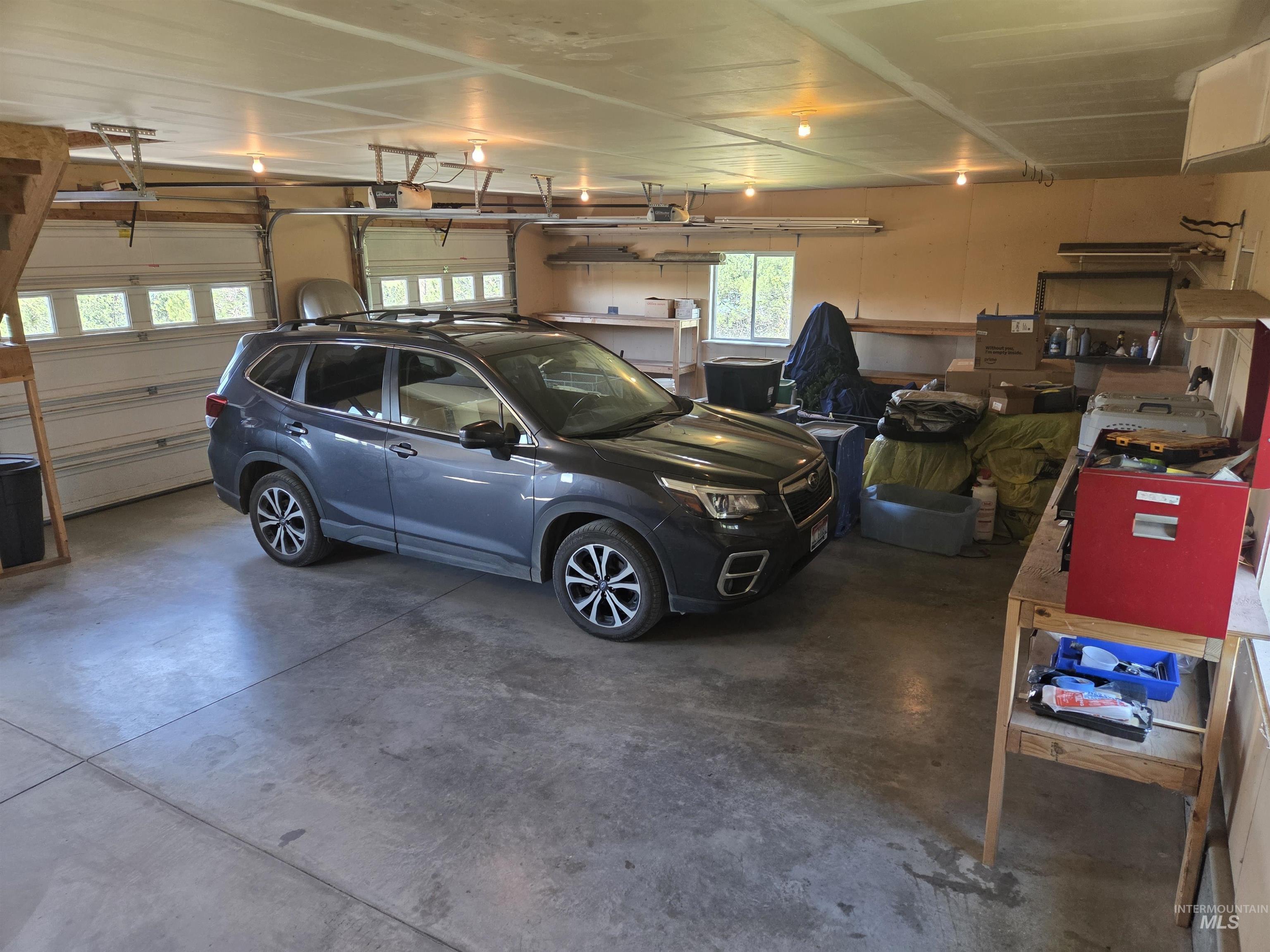 1085 Wallen Road Moscow, ID 83843 - Photo 32 of 50 Spacious garage featuring a concrete floor, multiple garage doors with upper window panels, exposed ceiling joists, and integrated overhead lighting
