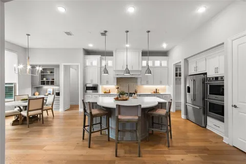 a dining room with stainless steel appliances kitchen island granite countertop a dining table chairs refrigerator and cabinets