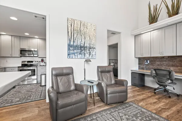 a living room with furniture wooden floor and a kitchen view