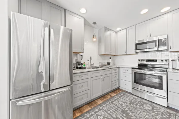 a kitchen with stainless steel appliances granite countertop a refrigerator sink and white cabinets