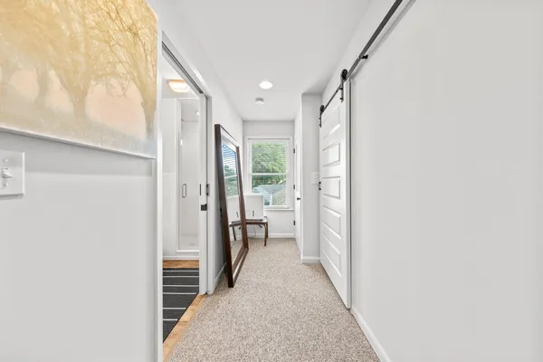 a view of a hallway with wooden floor and a bathroom