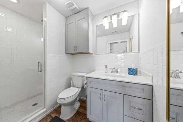 a bathroom with a toilet a sink a glass door a shower and a mirror