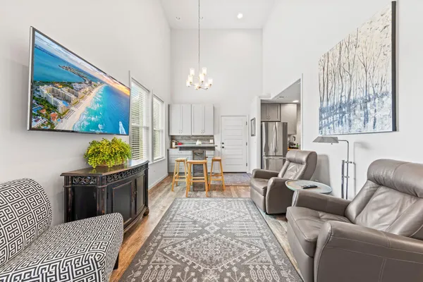 a living room with stainless steel appliances furniture a chandelier and a view of kitchen