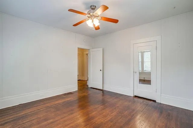 a view of an empty room with window and wooden floor